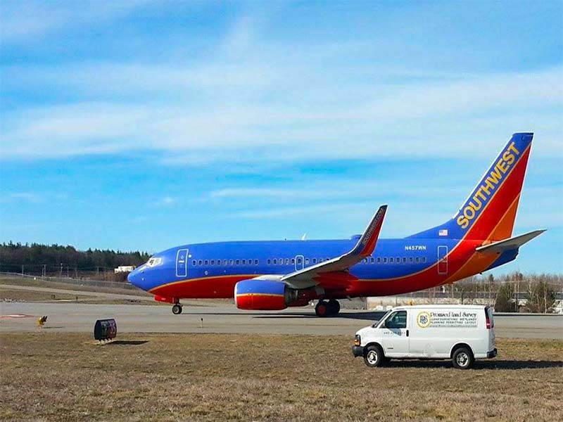 Promised Land Survey truck parked near a Southwest Airlines plane at Manchester Boston Regional Airport